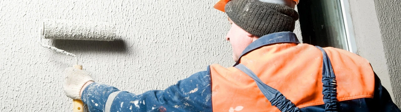 Robotník natiera budovu v zime