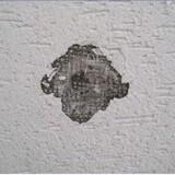 Diera na bielej stene domu, poškodená fasáda