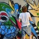 Muž kreslí graffiti na stenu