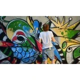 Muž kreslí graffiti na stenu