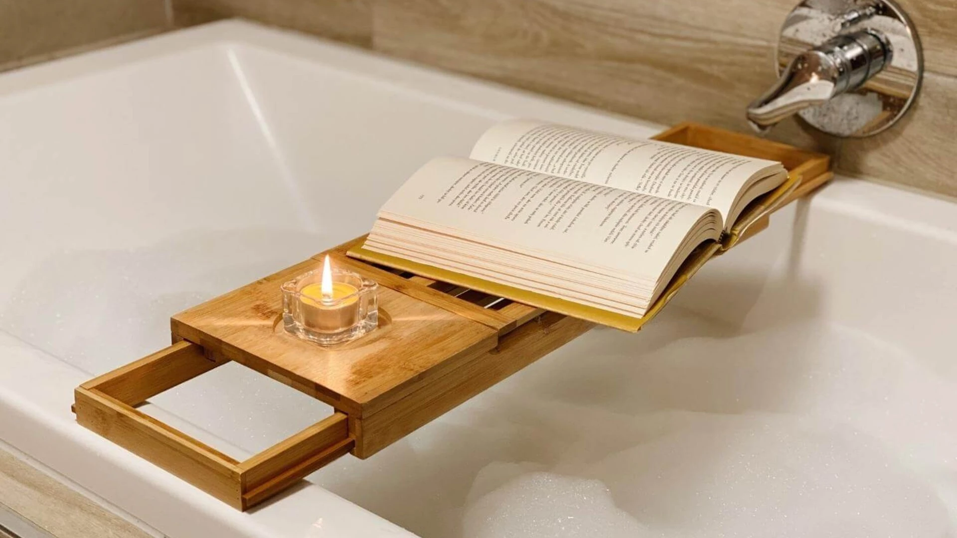 Kniha a sviečka položená na bambusovom stolčeku v napustenej vani