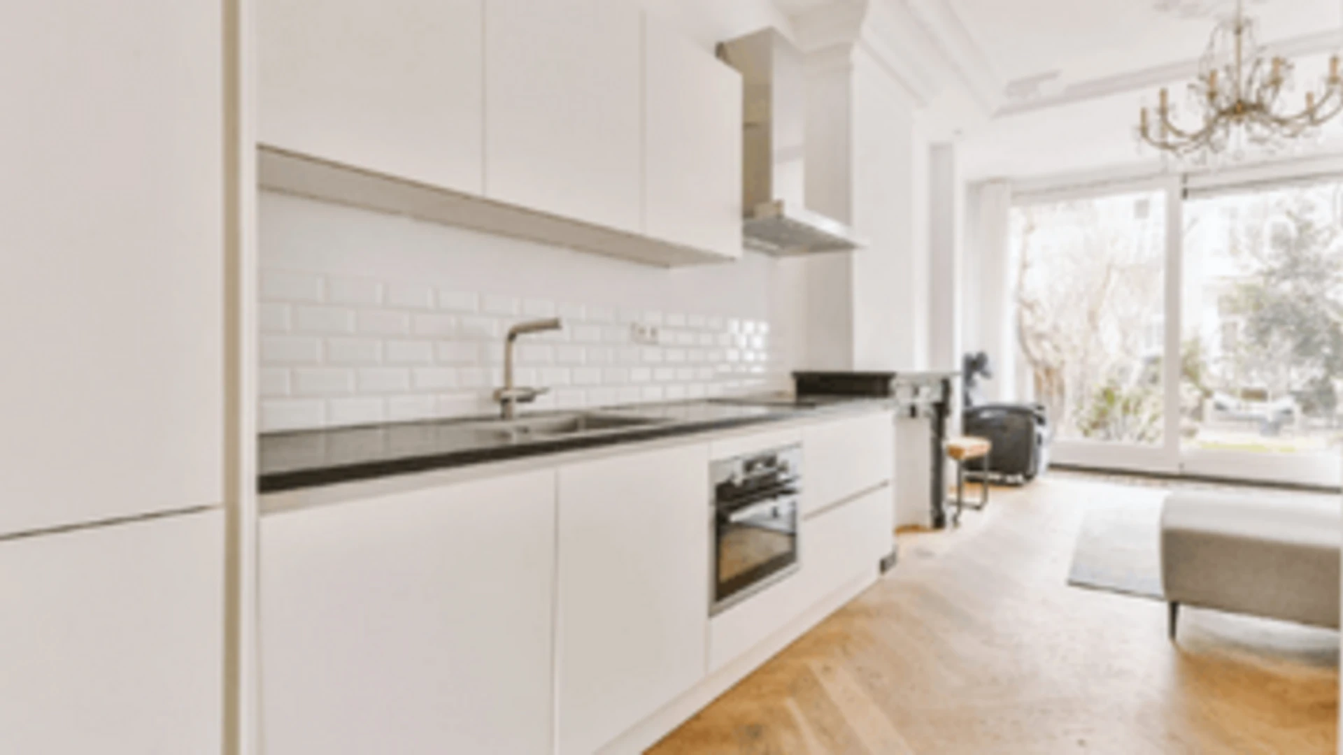 Minimalisticky zariadený byt s bielou kuchyňou.