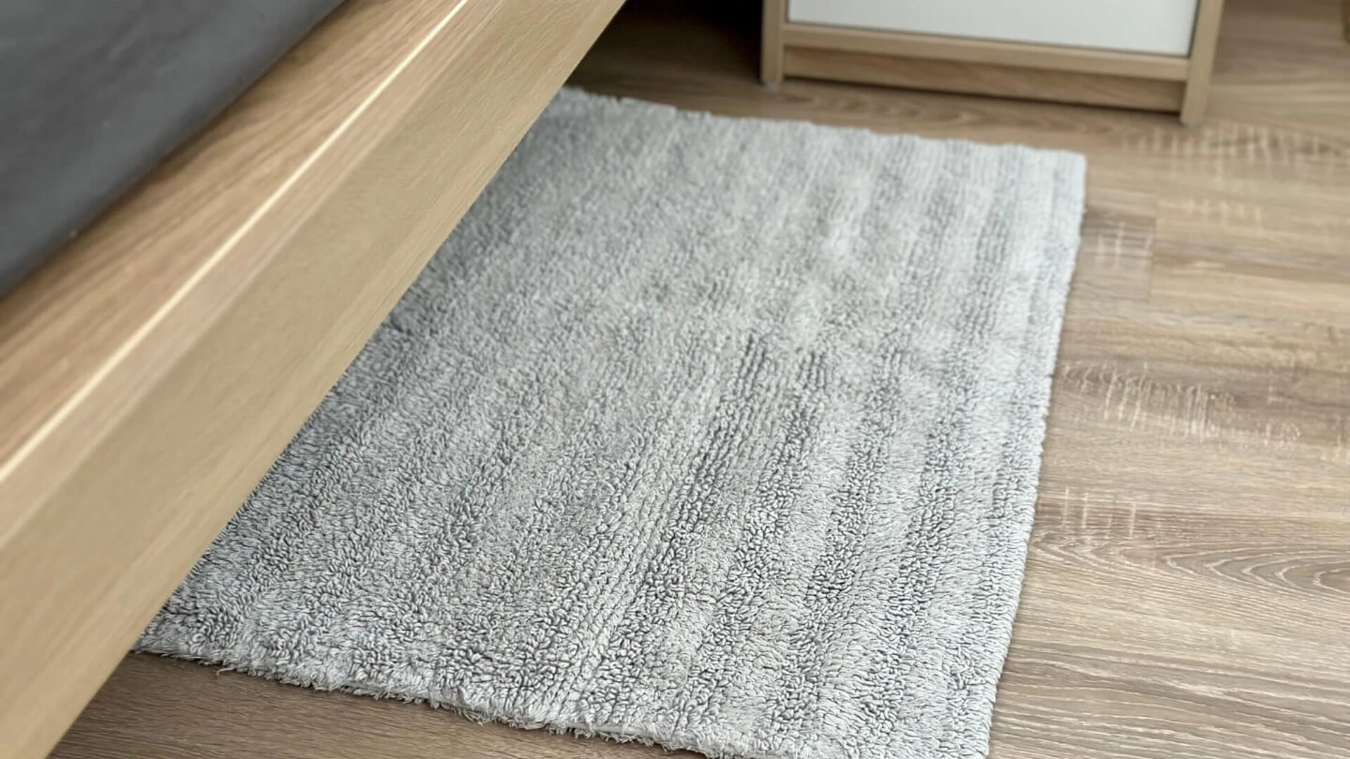 Malý šedý koberec pri posteli