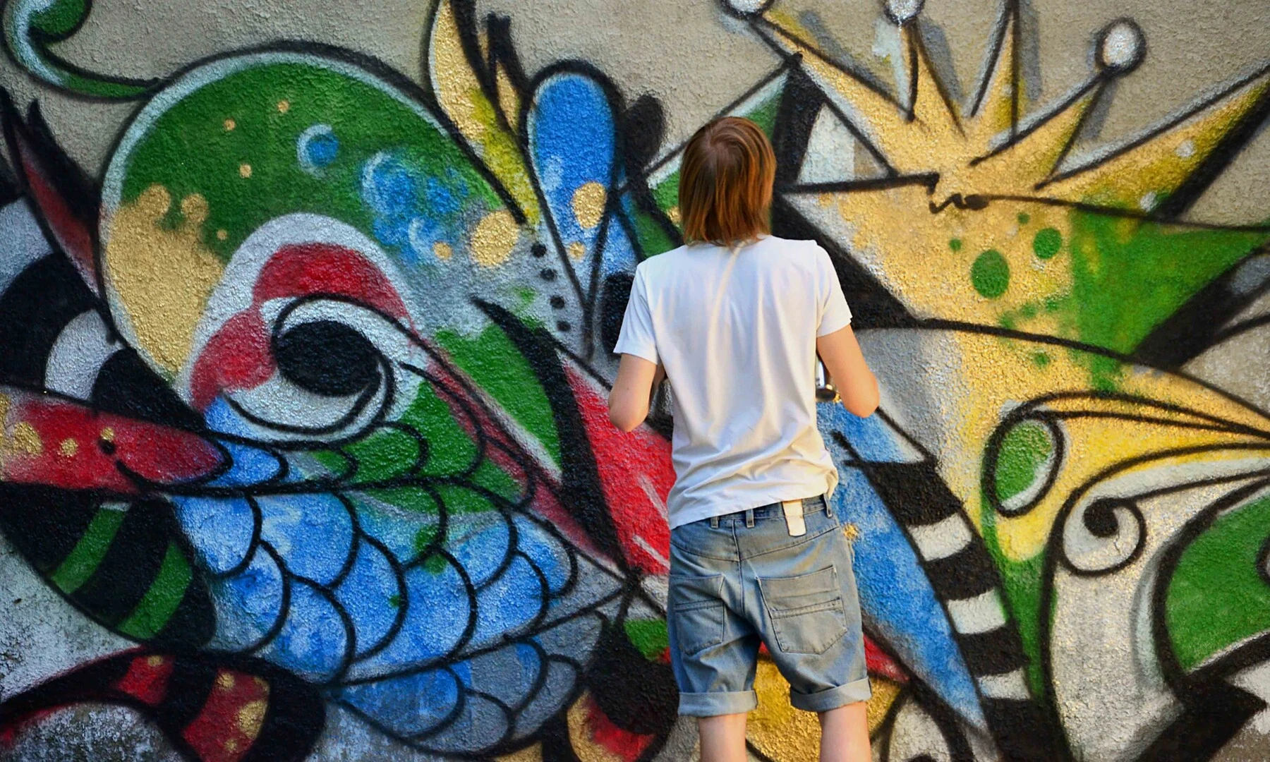Muž kreslí graffiti na stenu