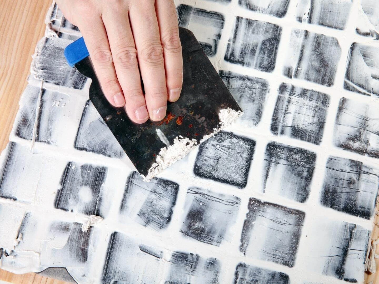 Škárovanie malých kachličiek bielou škárovacou hmotou. 