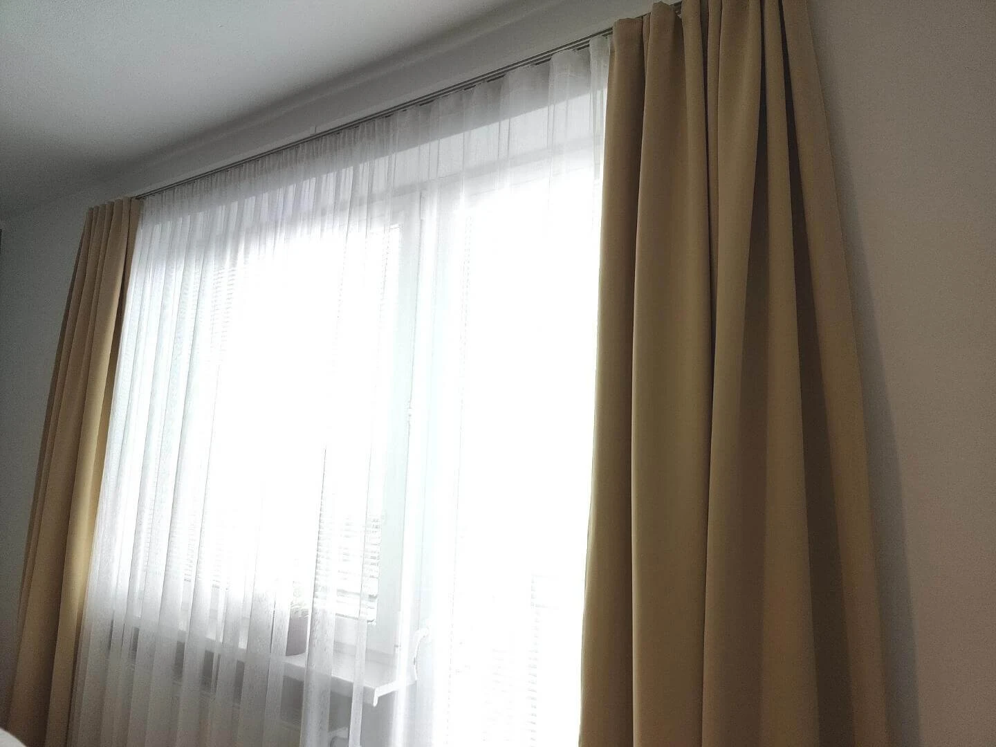 Jemná záclona a bledohnedé závesy po stranách okna
