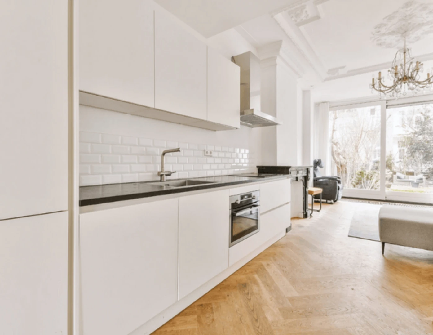 Minimalisticky zariadený byt s bielou kuchyňou.