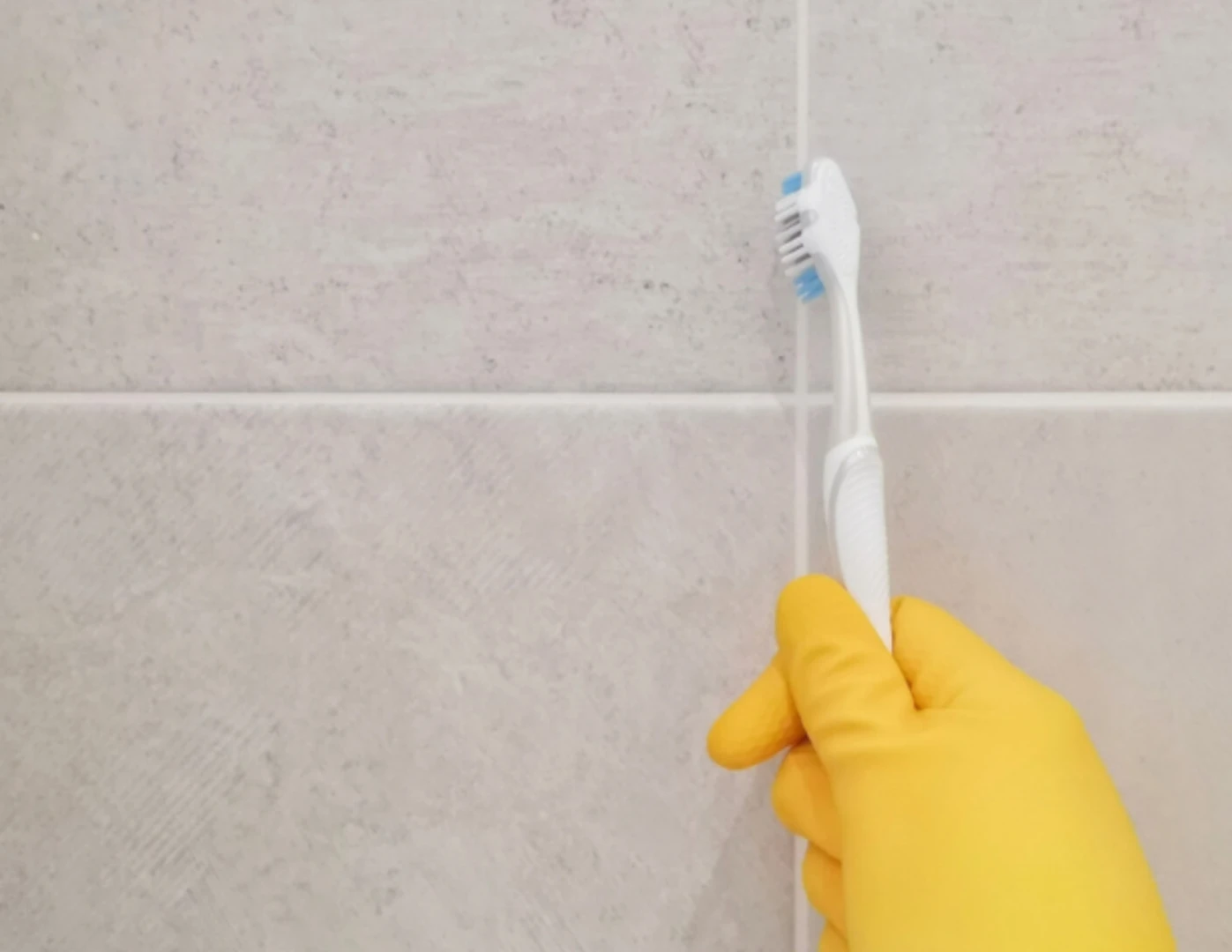Čistenie kúpeľňových škár zubnou kefkou.