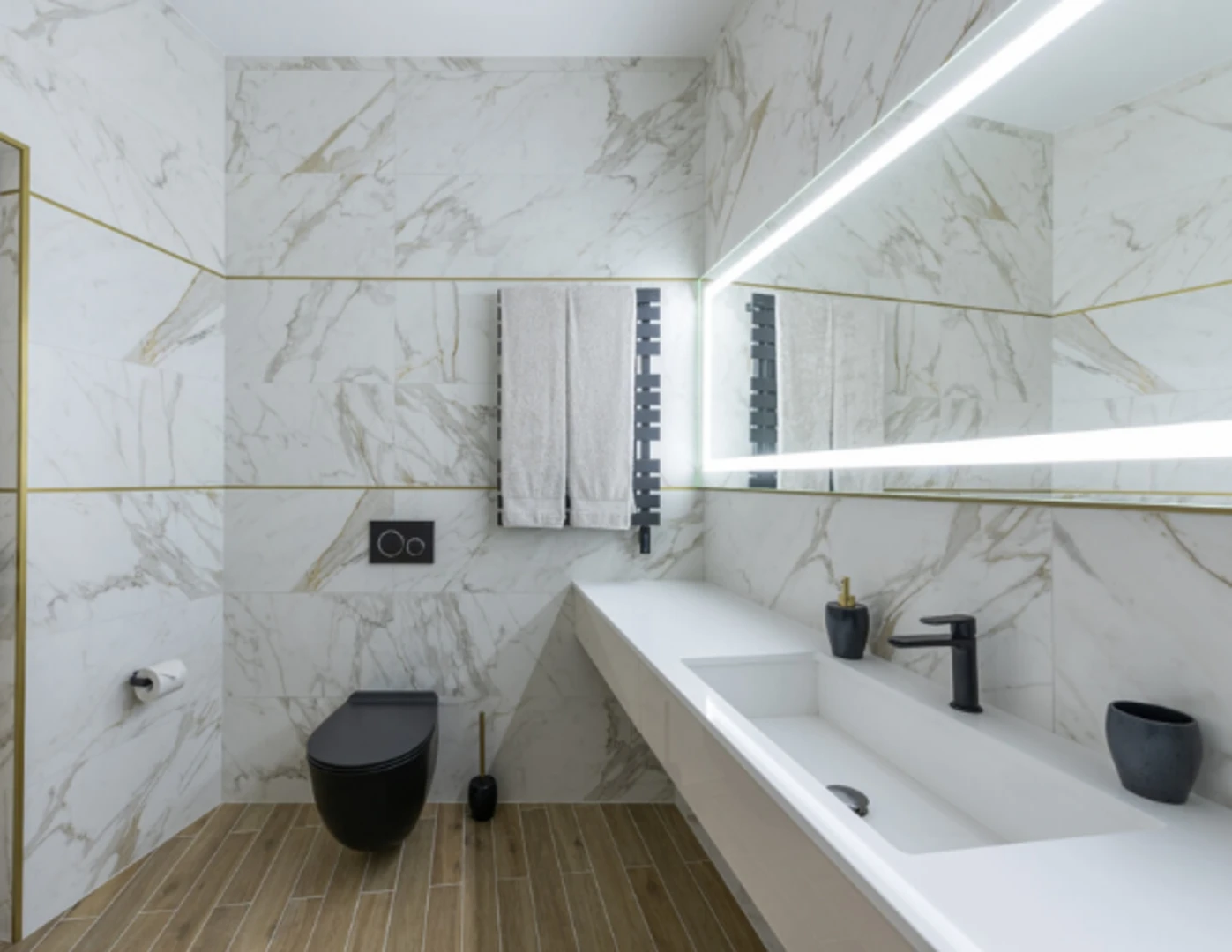 Čierna batéria v umývadle, toaleta, splachovanie, radiátor a drobné čierne doplnky v kúpeľni.