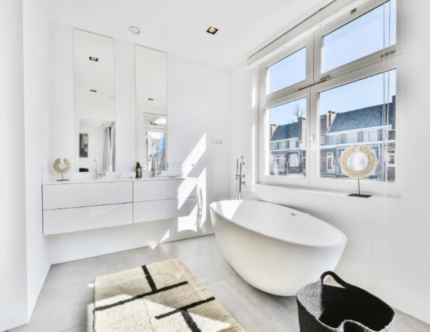 Krémovo-čierny koberček v bielej modernej kúpeľni.