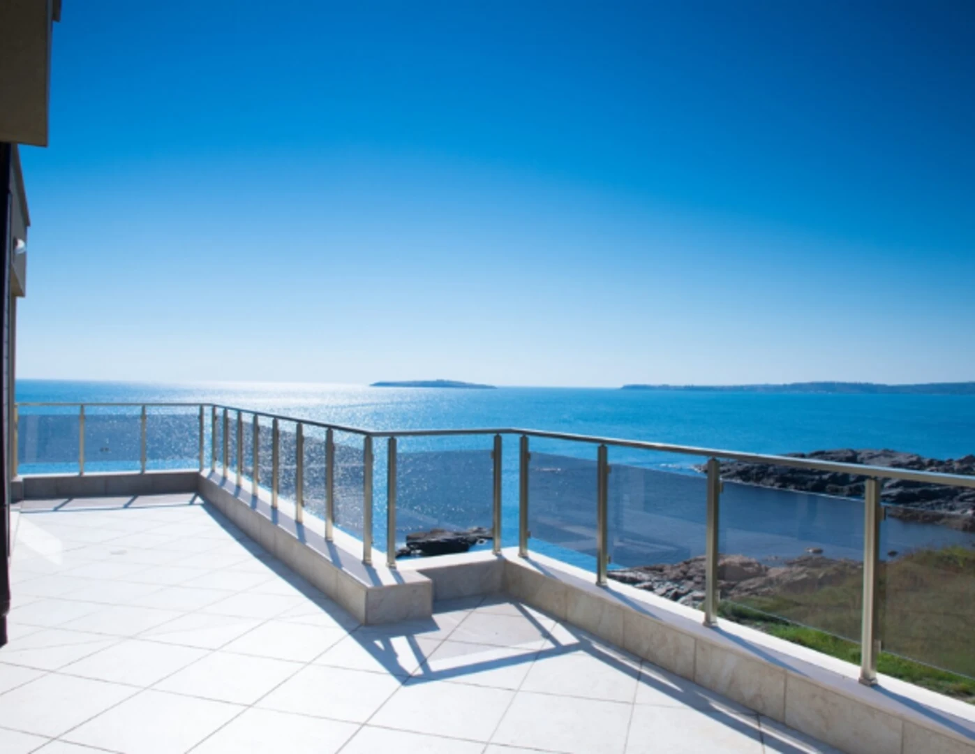 Terasa so zábradlím a v pozadí more.