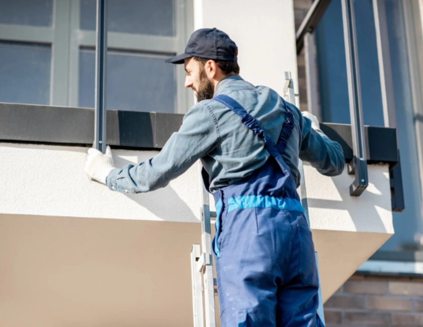 Muž montuje balkónové zábradlie.