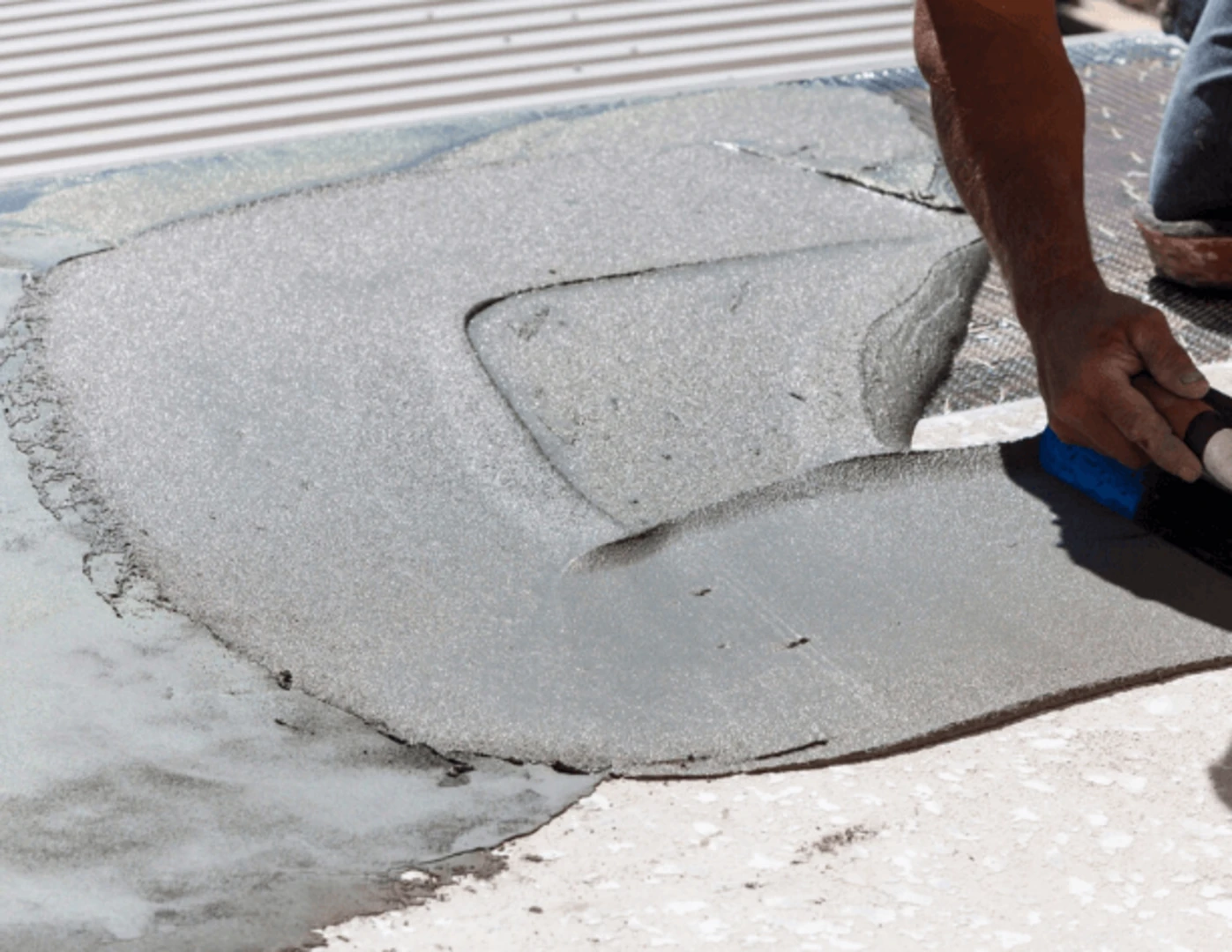 Muž nanáša náter pri oprave balkóna.