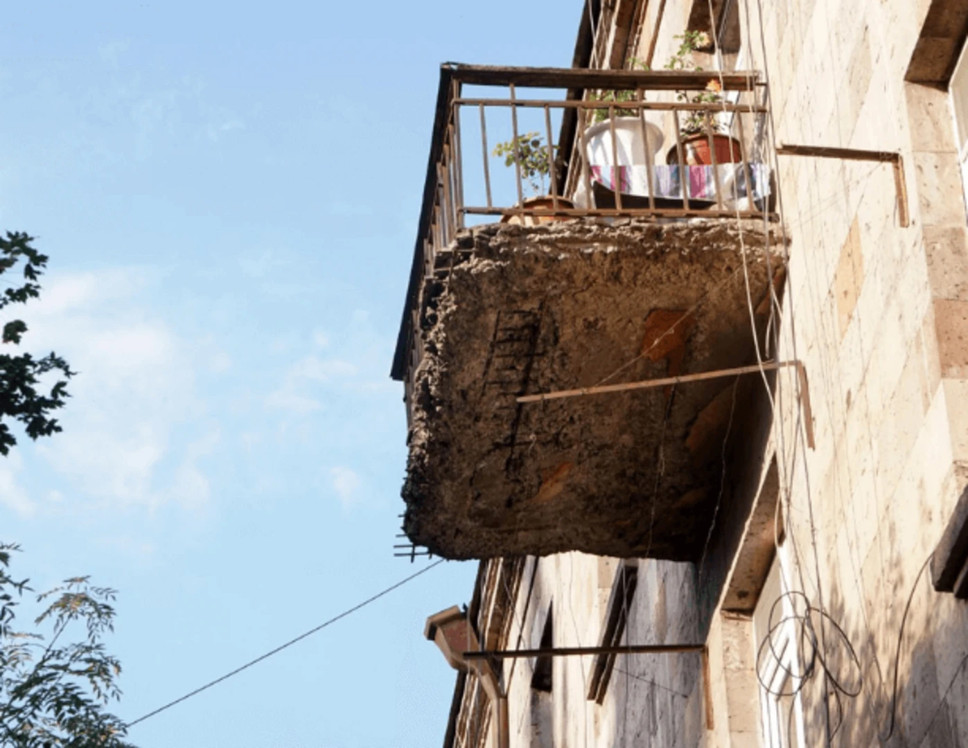 Pohľad na poškodenú konštrukciu balkóna zospodu.