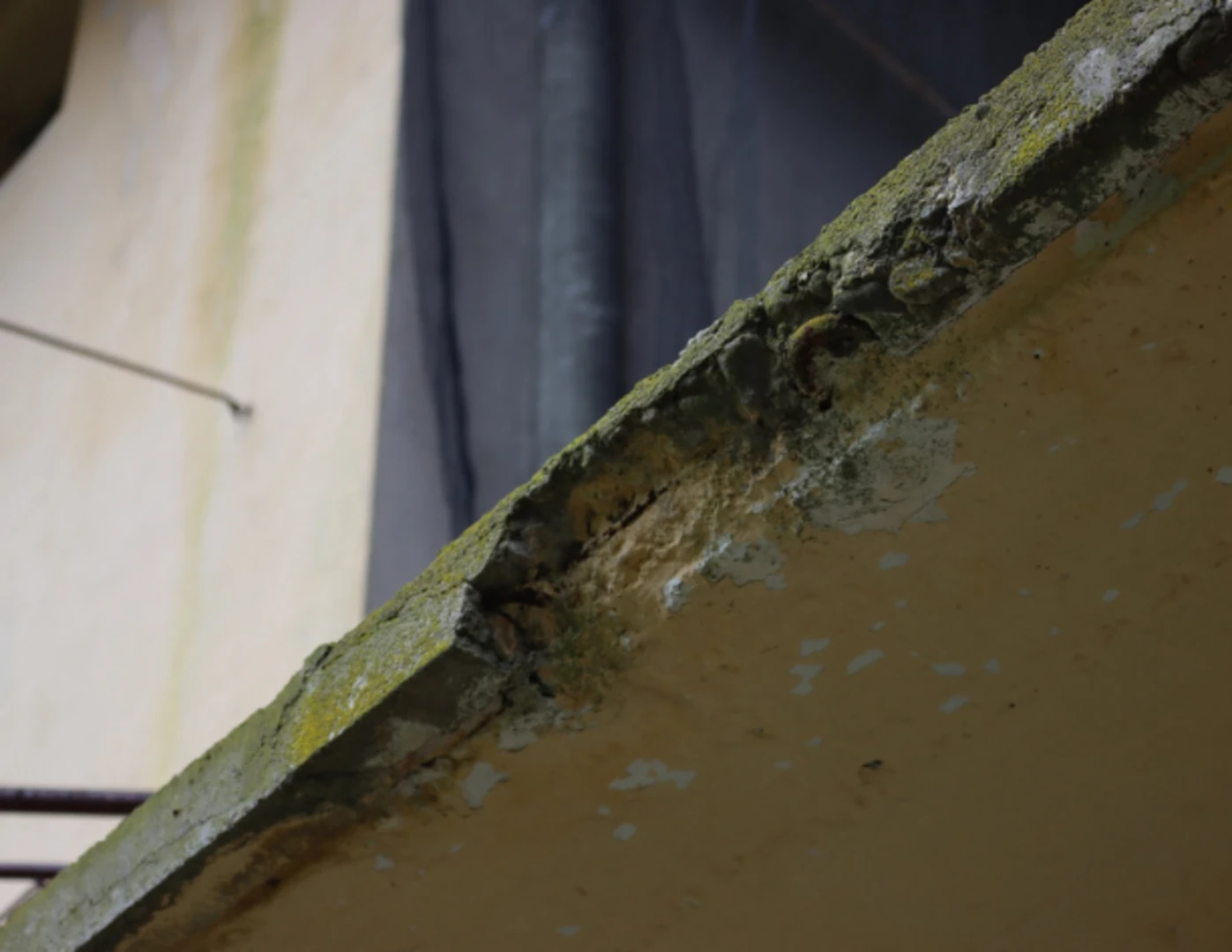 Detail na poškodenú betónovú konštrukciu balkóna.