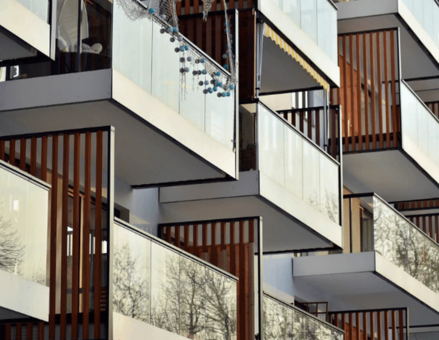 Presklené balkóny oddelené drevenými lamelami.