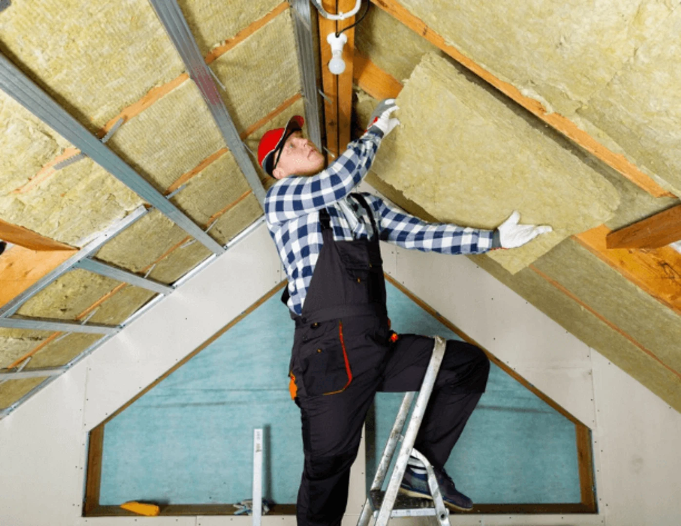 Muž zatepľujúci strechu podkrovia.