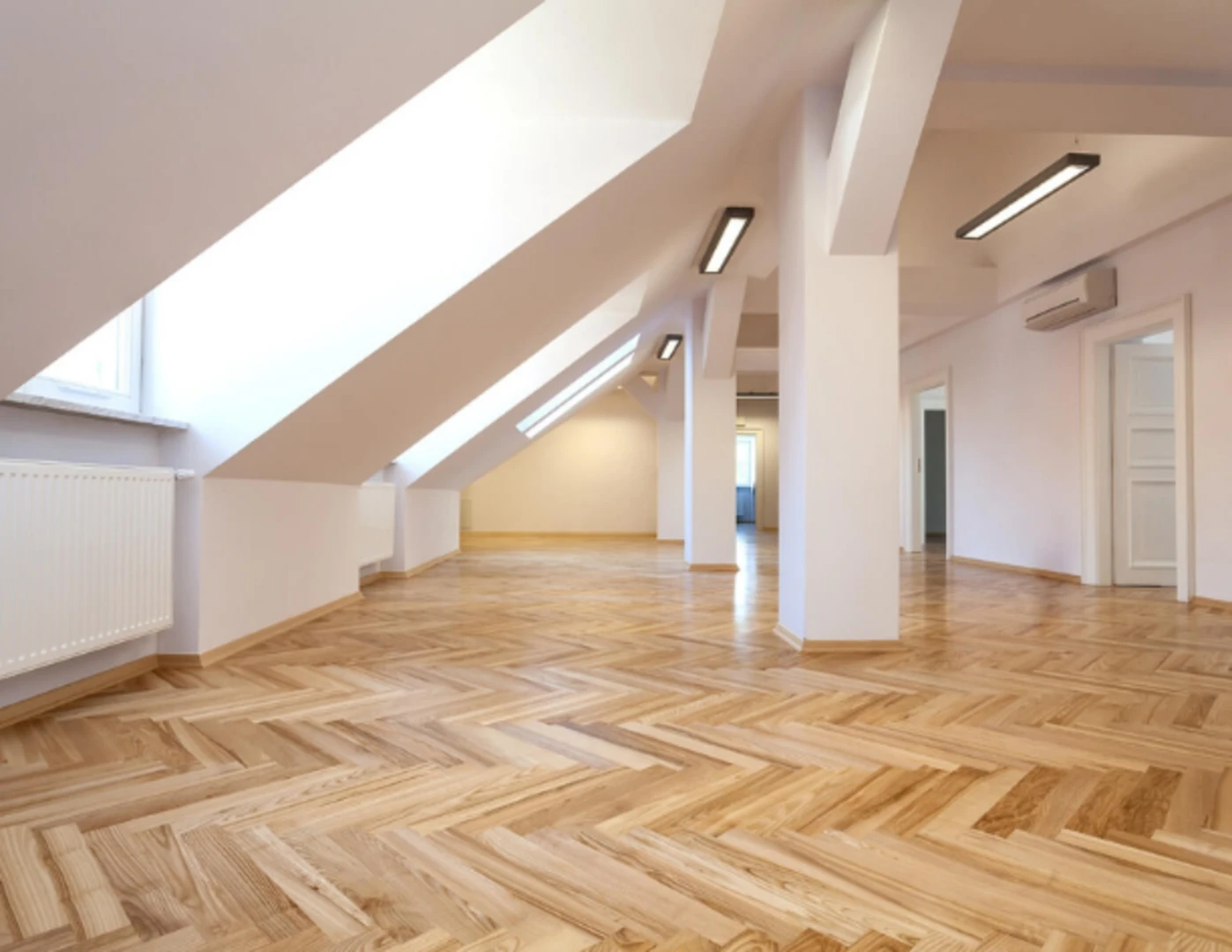 Zrekonštruované podkrovie s novými parketami a čerstvo namaľovanými bielymi stenami.