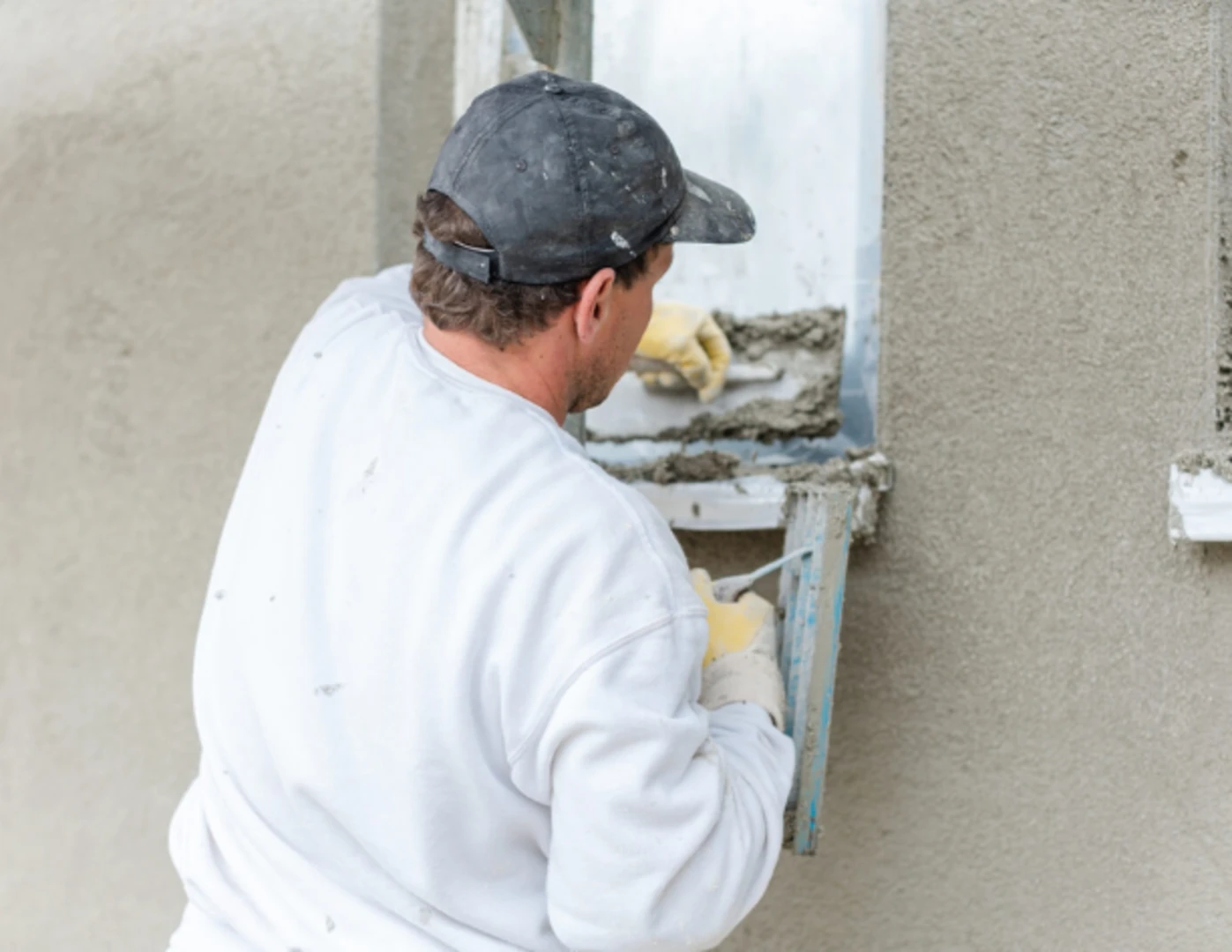 Pracovník nanáša omietku na stenu.