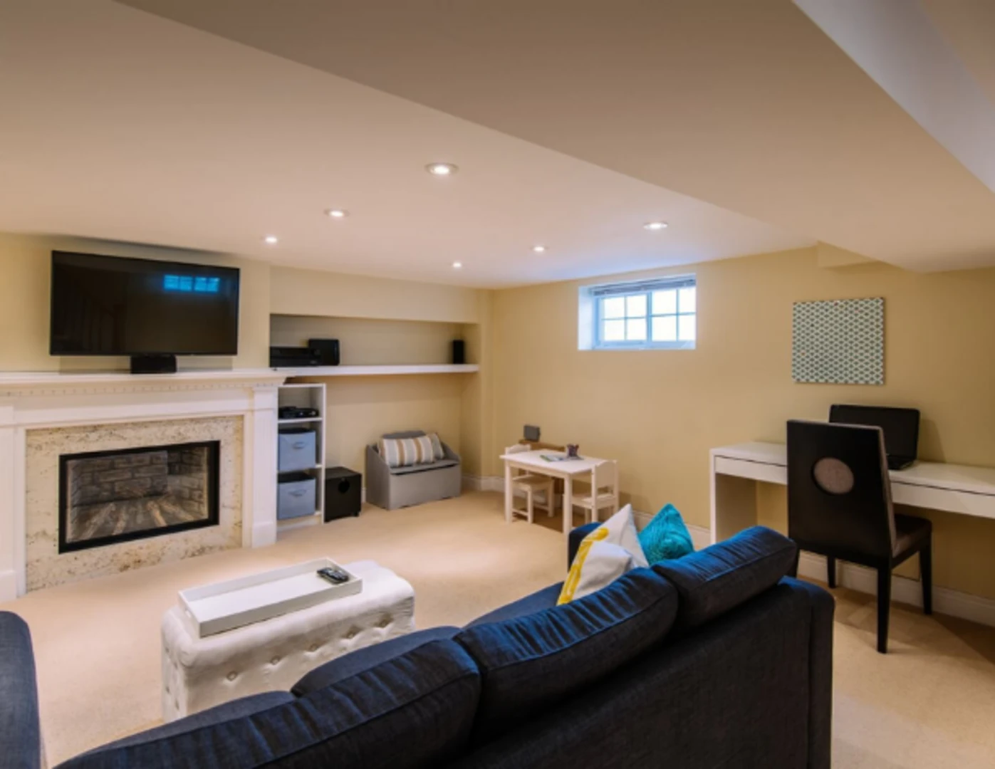 Zrekonštruovaná pivnica na rekreačnú miestnosť s TV, pracovným stolíkom a priestorom na hranie.