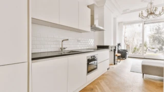 Minimalisticky zariadený byt s bielou kuchyňou.