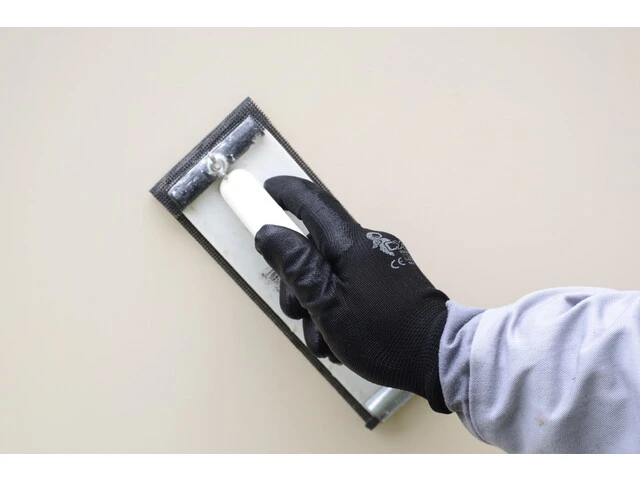 Prebrúsenie nerovností bielej omietky na fasáde hladidlom