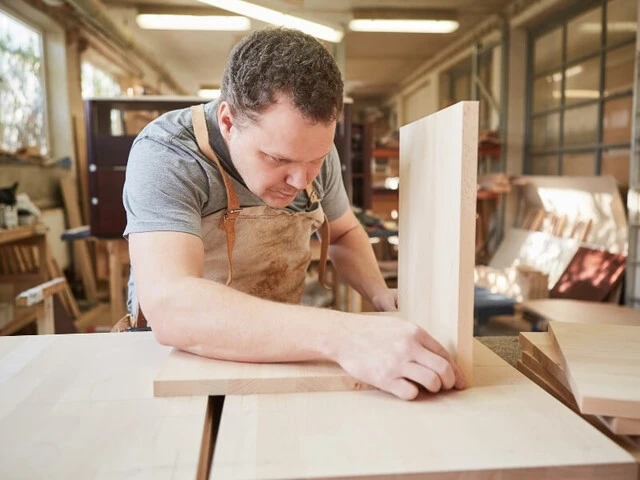 Muž stavia drevenú poličku