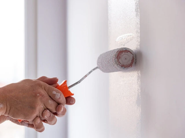 Maľovanie steny bielou farbou pomocou maliarskeho valčeka