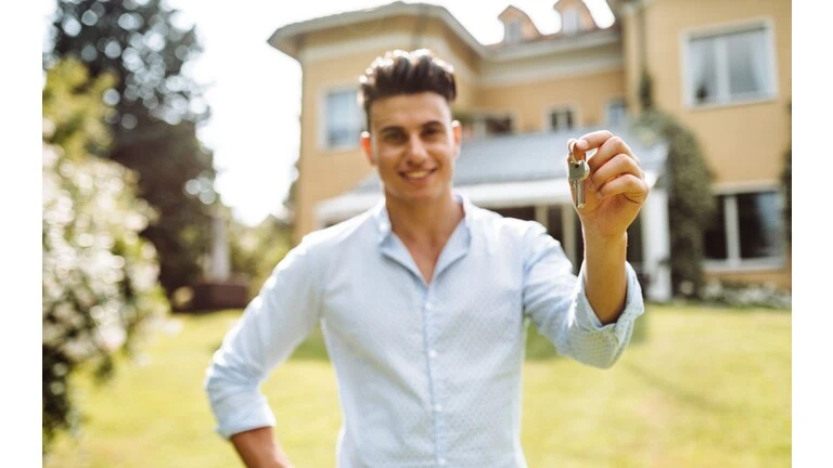 Investor a vlastník domu držiaci kľúč pred domom