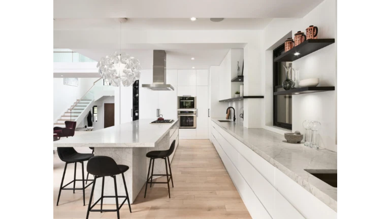 Moderná biela kuchyňa s mramorovou doskou a čiernymi detailmi.