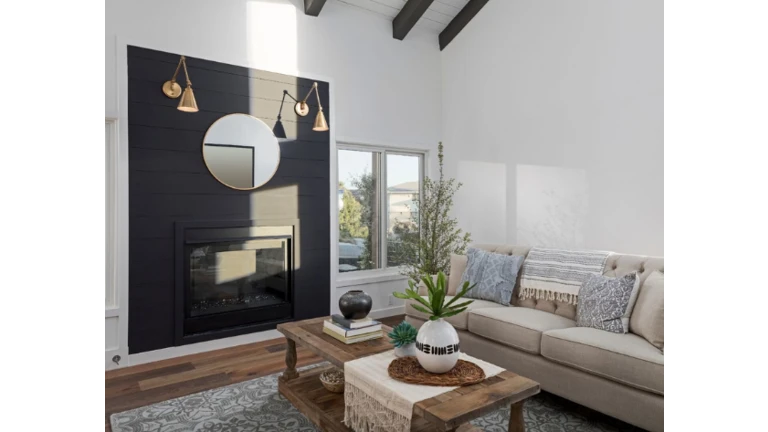 Obývačka s čiernym krbom, dizajnovými dekoráciami a ozdobnými vankúšmi na sedačke.