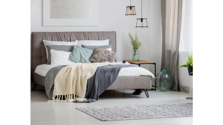 Manželská posteľ v spálni s ozdobnými dekami a vankúšmi.